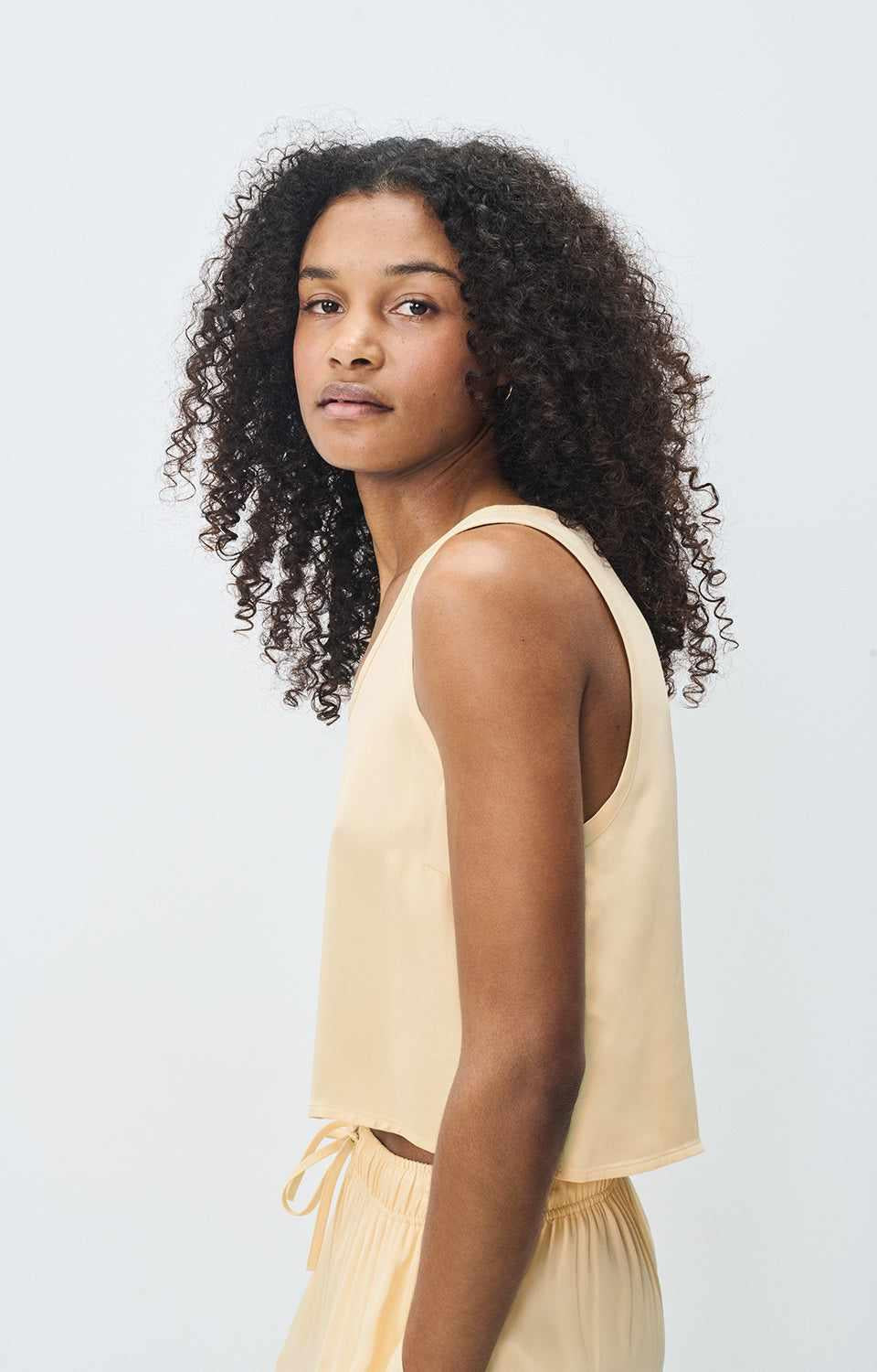 Model wearing American Vintage G-UNY07B viscose cami in butter yellow, side profile showing fluid drape and relaxed fit, at MEZI Australia.